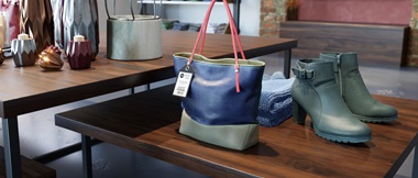 A handbag with a price tag sale label is on display in a retail store environment next to a pair of shoes